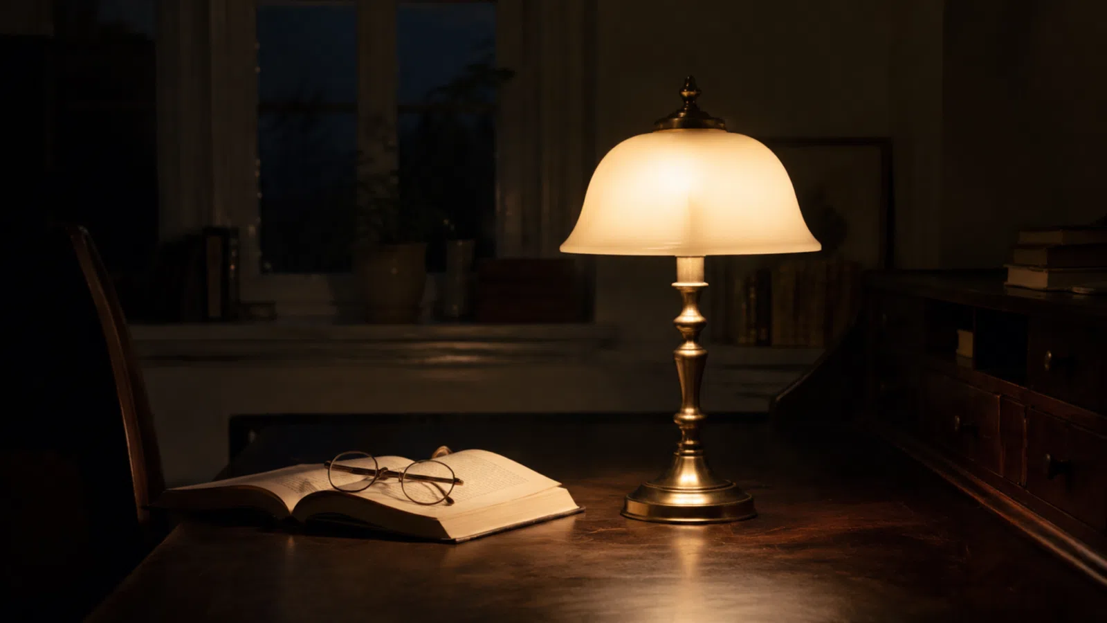 Strindbergslampa med kupad glasskärm och mässingsfot på ett skrivbord